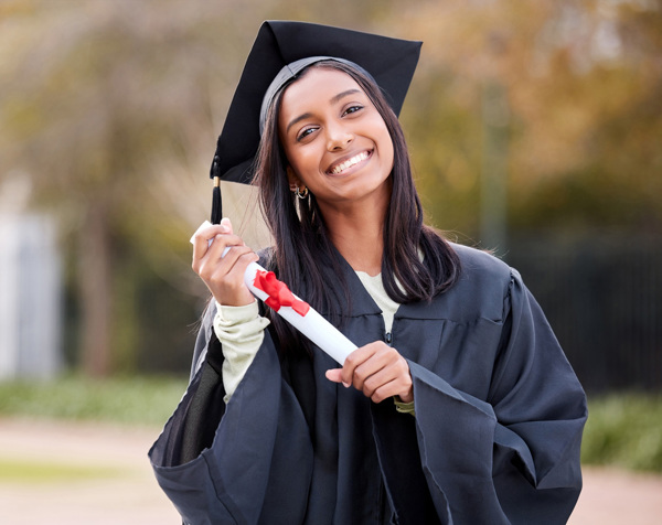Girl smiling while wearing a graduation gown and cap holding a diploma